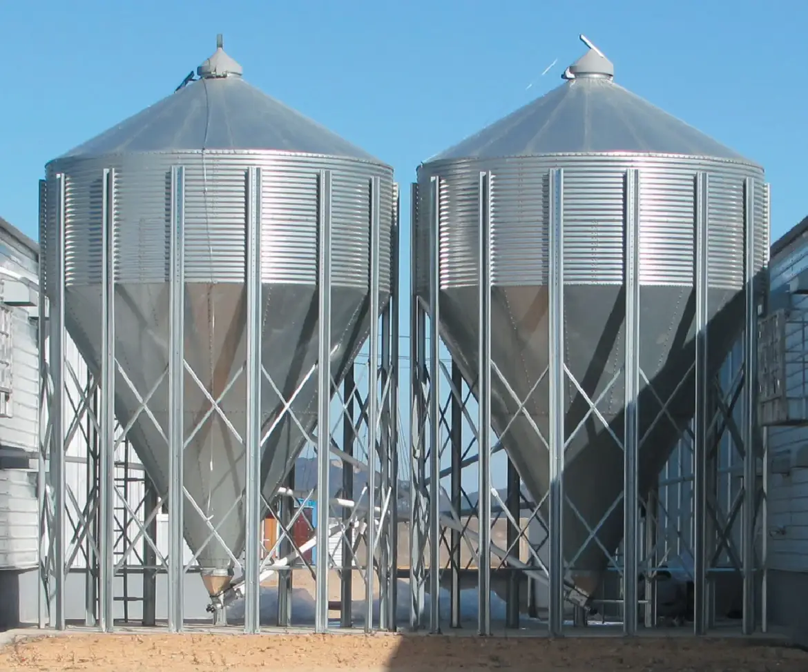 Two galvanised feed storage silos beside a poultry house